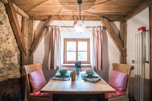a dining room table with two chairs and a window at Das Schusterhäusl - Urlaub im oberbayerischen Baudenkmal in Samerberg
