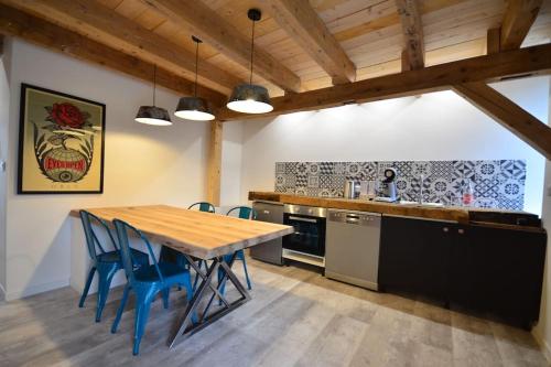 a kitchen with a wooden table and blue chairs at L’Etable in Breitenbach-Haut-Rhin