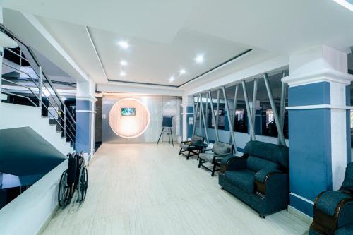 a living room with a couch and chairs and a staircase at Hotel Athome , Whitefields, Kondapur in Hyderabad