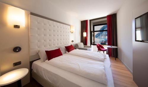 a bedroom with a large white bed with red pillows at Hotel Centrale in Riva del Garda