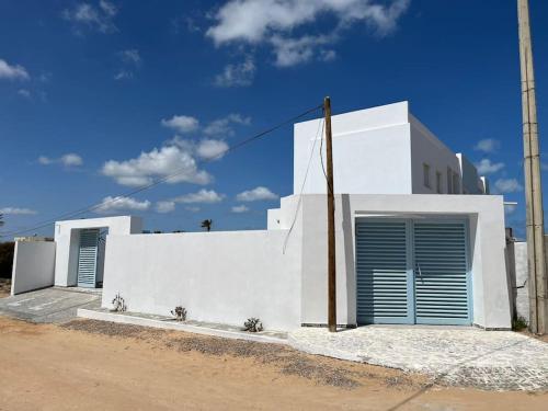 a white building with blue doors on the side of it at Studio Bleu Cosy à Dar Lili Djerba in Mezraya