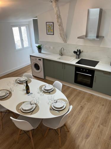 a kitchen with a white table and chairs in a kitchen at LOFT COSY - CENTRE HISTORIQUE climatisé in Revel
