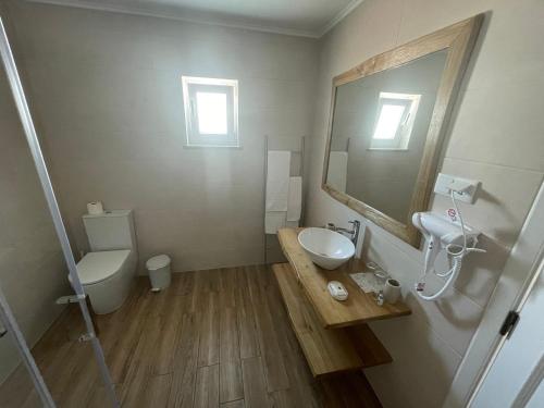a bathroom with a sink and a toilet and a mirror at Alojamento Sudoeste in Zambujeira do Mar