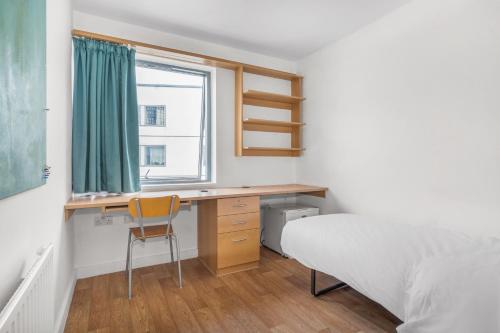 una camera da letto con scrivania, letto e finestra di Friendship House (Southwark) a Londra