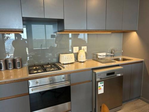 a kitchen with a stove top oven next to a sink at Umhlanga Arch Sea View Apartment in Durban
