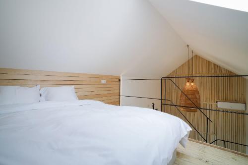 a bedroom with a white bed and a staircase at Kub House Village in Slănic-Moldova