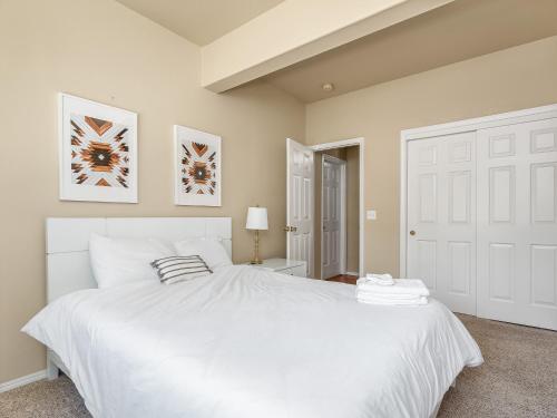 a white bedroom with a large white bed with two pillows at Home oasis with sauna, jacuzzi, pool & heated gazebo! in Clovis