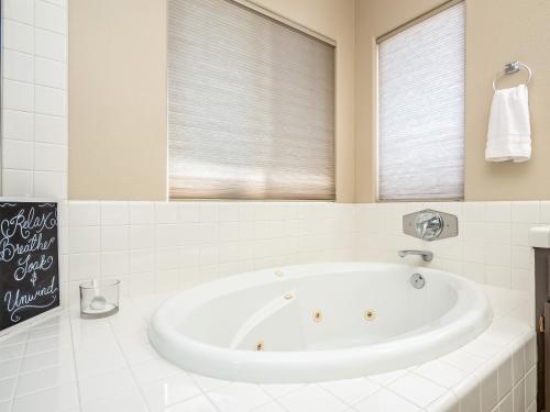 a white bath tub in a bathroom with a window at Home oasis with sauna, jacuzzi, pool & heated gazebo! in Clovis