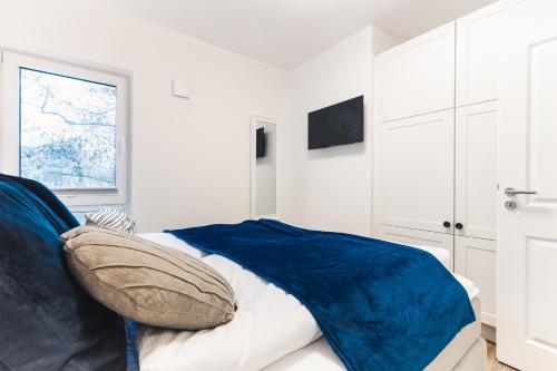 ein weißes Schlafzimmer mit einer blauen Decke auf einem Bett in der Unterkunft Kranichruf in Müggenburg