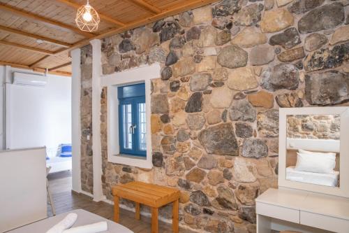 a stone wall in a room with a table and a mirror at Melina Seafront Stone House in Kardamaina
