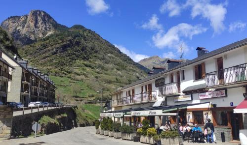 una calle en una ciudad con montañas en el fondo en Hostal Los Valles, en Bielsa