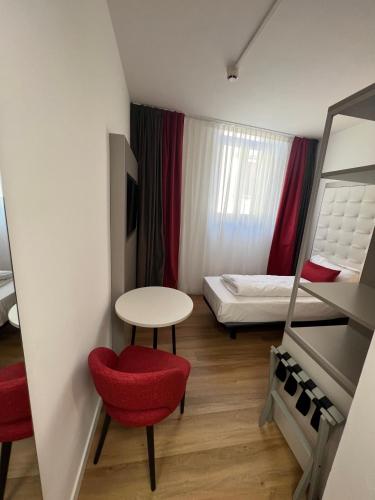 a small room with a red chair and a table and a bed at Hotel Centrale in Riva del Garda