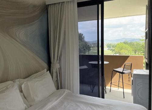 a bedroom with a bed and a balcony with a table at Brand new Condo in Laguna near golf course in Bang Tao Beach