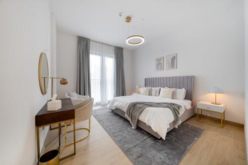 2 Bedroom Apartment by the beach at Port De La Mer-Dubai في دبي: غرفة نوم بيضاء مع سرير ومكتب