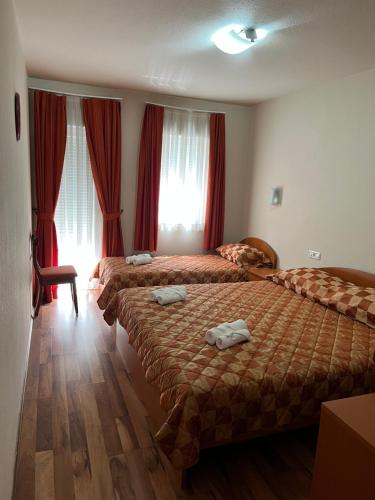 2 łóżka w pokoju hotelowym z czerwonymi zasłonami w obiekcie PANSION KATA w Medziugorie