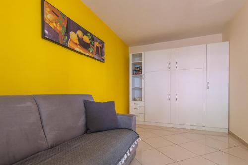 salon z kanapą i żółtą ścianą w obiekcie Studio St Jean à Roquebrune, proche Menton et Monaco w mieście Roquebrune-Cap-Martin