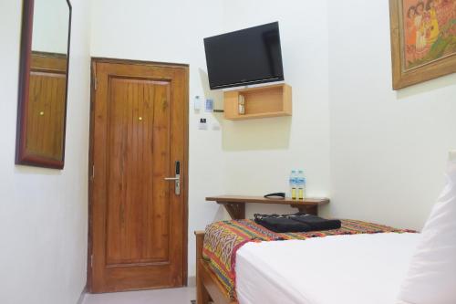 a bedroom with a bed and a door with a television at The Cabin Hotel Ambasador in Yogyakarta