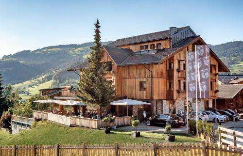 un gran edificio de madera con un restaurante delante de él en ALMMONTE SENSUM SUITES Boutique Hotel en Wagrain