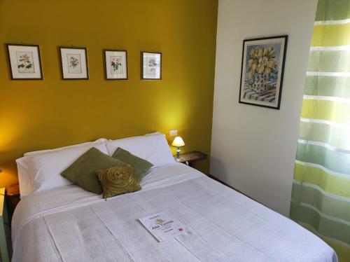 a bedroom with a white bed with pictures on the wall at Alle Terme B&B in Rapolano Terme