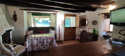 ein Wohnzimmer mit einem Tisch und einem TV in der Unterkunft La Casería in Navaconcejo