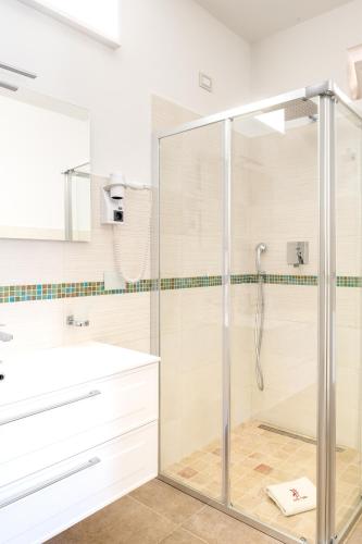 a glass shower in a bathroom with a sink at MILLE SUITE GARDEN in Noto