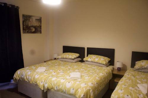 a bedroom with two beds with yellow comforter at Elm Tree Guest House in Weston-super-Mare