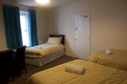 1 dormitorio con 2 camas y ventana en Elm Tree Guest House, en Weston-super-Mare