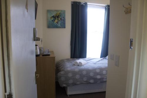 a small bedroom with a bed and a window at Elm Tree Guest House in Weston-super-Mare