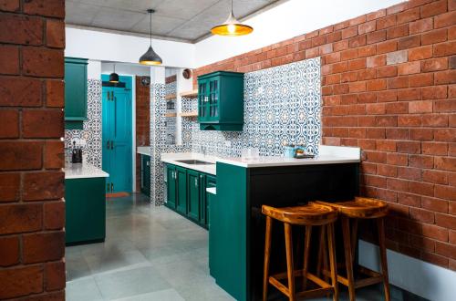 a kitchen with green cabinets and a brick wall at Tentgram Brickhouse in Kozhikode