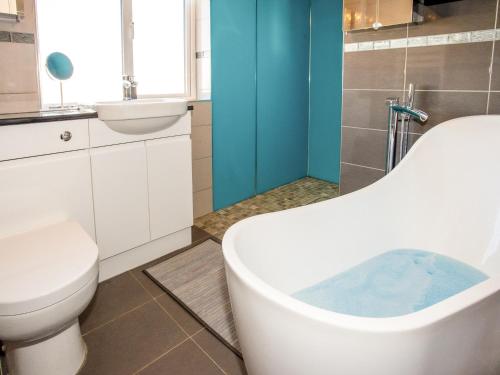 a bathroom with a tub and a toilet and a sink at Dreamcatcher in South Hayling