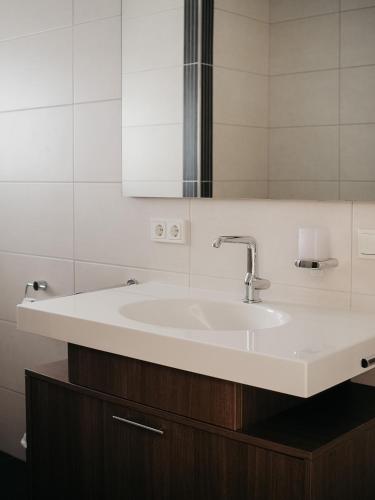 W łazience znajduje się biała umywalka i lustro. w obiekcie Appartement Meyer-Ernzen w mieście Echternach