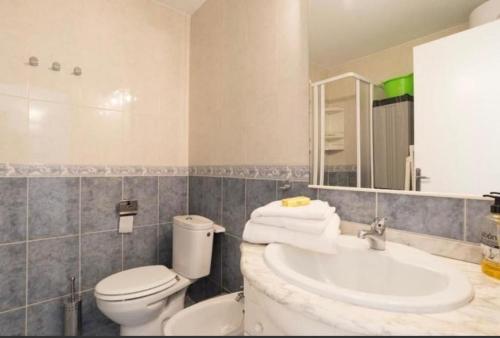 Un baño con lavabo, inodoro y espejo. en Studio La Carihuela, en Torremolinos