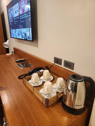 a tea kettle and saucers on top of a table at HOTEL HERENCIA 625 formerly Abaca Suites in Daraga