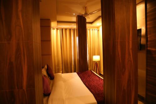 a bedroom with a bed and a lamp and curtains at Perfectstayz Premium Ganga Heights at Harkipauri Road in Haridwār