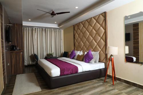 a bedroom with a large bed with purple pillows at Perfectstayz Premium Ganga Heights at Harkipauri Road in Haridwār