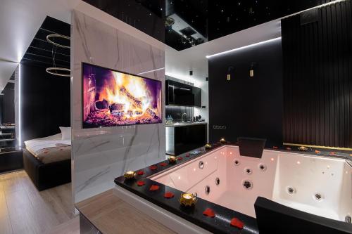 a large bathroom with a tub with a tv on the wall at Wiślane Tarasy VIP Apartamenty JACUZZI in Kraków