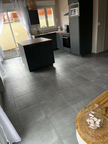 Il comprend une cuisine dotée de carrelage, d'un comptoir et d'une table. dans l'établissement La maison des dunes, à Berck-sur-Mer