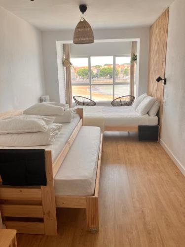 2 Betten in einem Zimmer mit einem großen Fenster in der Unterkunft Boogalow Hostel in Gijón