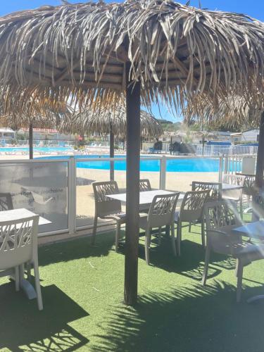 a table and chairs under a straw umbrella on a beach at Mobile home Zen Siblu Fréjus in Fréjus