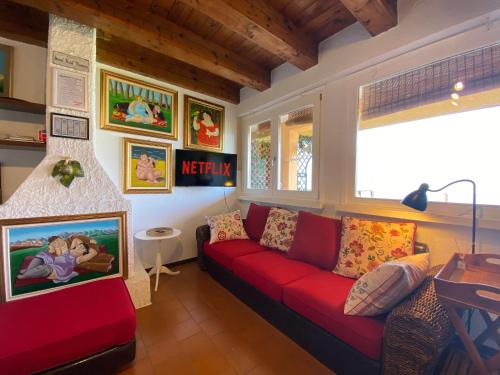 uma sala de estar com um sofá vermelho e quadros na parede em Casa Vista lago - 24h Check in - Free WiFi - Netflix em Monte Isola