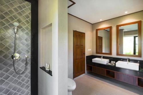 a bathroom with two sinks and a toilet and two mirrors at Residence Lake Rawai in Phuket Town