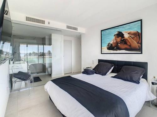 ein Schlafzimmer mit einem großen Bett mit einem Bild an der Wand in der Unterkunft Magnifique appartement vue mer in Vallauris