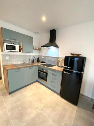 La cuisine est équipée d'un réfrigérateur noir et d'un évier. dans l'établissement L'Escale Marine, à Saint-Lunaire