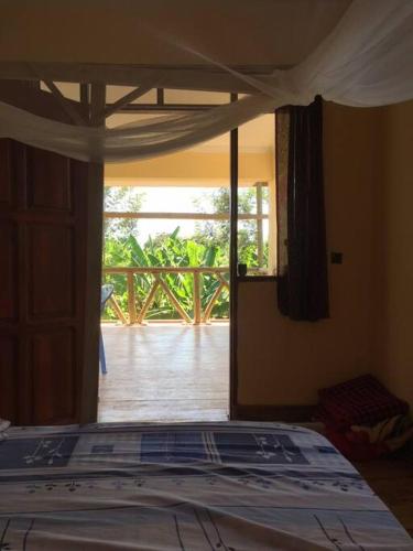 a bedroom with a bed with a view of a porch at Hondo Hondo House in Mto wa Mbu