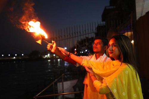a man and a woman holding a fire lighter at Perfectstayz Premium Ganga Heights at Harkipauri Road in Haridwār