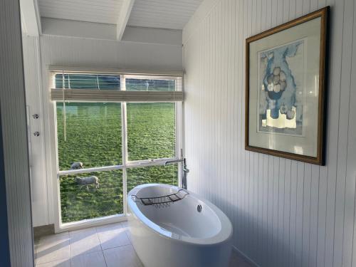 a white bathroom with a tub and a window at Seacroft Beach House in Sugarloaf