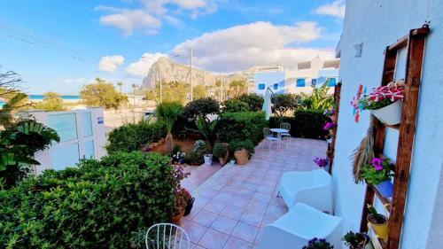 a patio with white chairs and plants and a building at Alba Chiara B&B in San Vito lo Capo