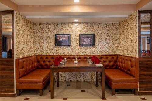 ein Esszimmer mit einem Tisch und Ledersitzen in der Unterkunft Summit Oakden Resort & Spa Mall Road in Darjeeling