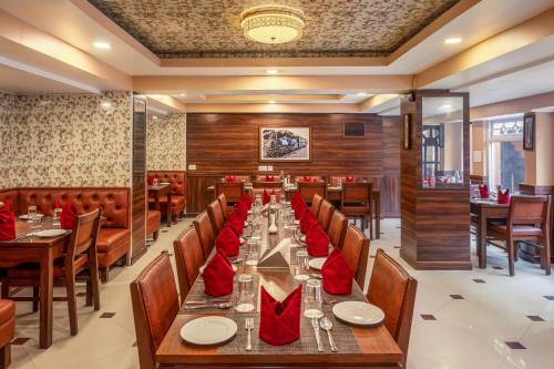 a dining room with a long table with red napkins at Summit Oakden Resort & Spa in Darjeeling