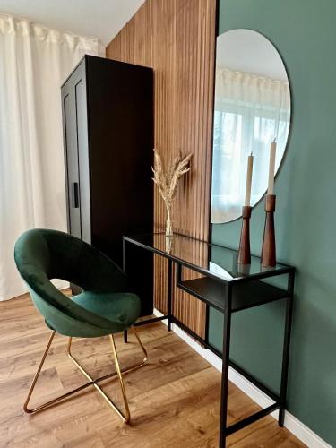 a green chair sitting next to a desk with a mirror at Weich wie Samt am Bodensee in Kressbronn am Bodensee
